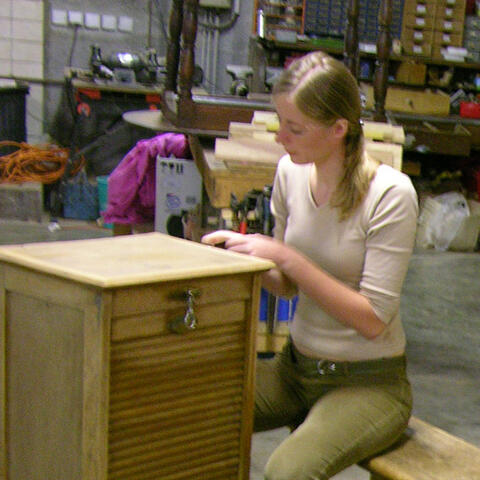Restauration d'un meuble dans un atelier Emmaüs
